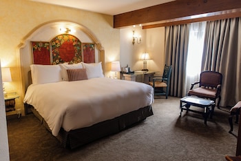 An outdoor dining area with a table set for two, surrounded by stone walls and potted plants.
