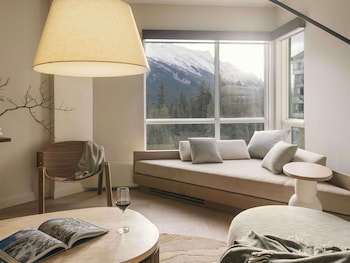 An outdoor seating area with fire pits, umbrellas, and a view of trees and mountains.
