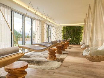 An outdoor seating area with fire pits, umbrellas, and a view of trees and mountains.