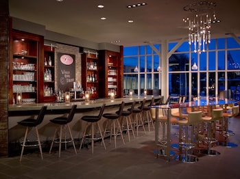 A bar area with a long counter, stools, and a view of the outside at dusk.