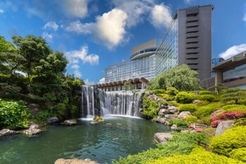 A view of a waterfall through a glass window, with red seating and a table in the foreground.