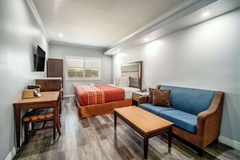 Een hotelkamer met een groot bed, een badkamer met een marmeren badkuip en oranje wanden.