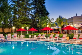 Relax by the serene pool surrounded by lush greenery and comfortable lounge chairs.