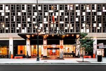 Un edificio moderno con un letrero que dice "the CURTIS" y una entrada bien iluminada.