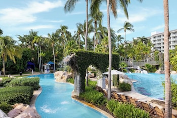 Relax by the central pool surrounded by lush palm trees and tropical vegetation.