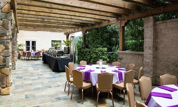 Un hall amplio con un muro decorativo de piedra, una mesa de recepción, una zona de estar con una mesa de centro y una escalera.