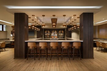Un amplio vestíbulo de hotel con varias zonas de restauración, diferentes disposiciones de asientos y un espacio central abierto.