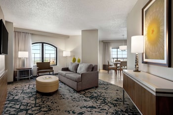 A spacious lobby with a modern design, featuring a curved seating area, a reception desk, and a large chandelier.