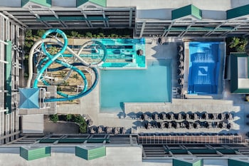 A water park with multiple slides and water features, surrounded by a multi-story building with balconies.