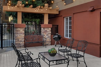 A stone facade with a sign for Larkspur Landing Home Suite Hotel, a lantern, and a flower bed.