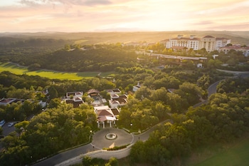 A resort with a swimming pool, lounge chairs, and a view of the surrounding landscape.