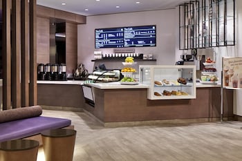 A spacious lobby with a high ceiling, large windows, and a central seating area with chairs and a table.