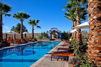 Una piscina al aire libre, sombrillas, sillones reclinables de piscina