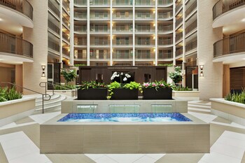 Un vestíbulo de hotel de varios niveles con zonas de estar, plantas y una escalera.