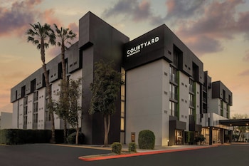 A modern building with a covered entrance, large windows, and a paved area with marked parking spaces.