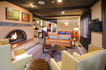 Un amplio salón con chimenea, un sofá confortable, un escritorio con computadora y una televisión.
