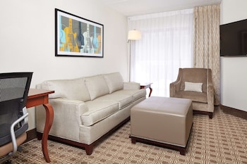 Amplia sala de estar con un patrón de suelo en espiga, una escalera y un área de descanso con muebles modernos.