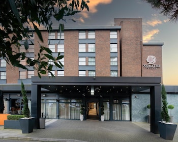 A DoubleTree by Hilton hotel with a brick facade, large windows, and a well-maintained lawn.