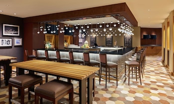 A spacious lobby with high ceilings, large windows, and a central seating area with sofas and armchairs.