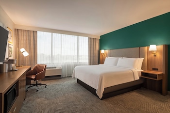 Hotelkamer met een groot bed, een bureau met stoel, een flatscreen televisie, een koffiezetapparaat en uitzicht op de stad.