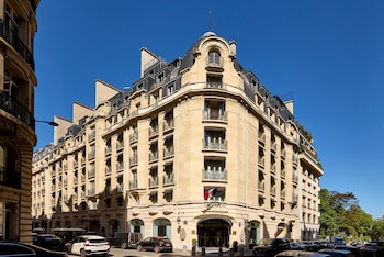 A multi-story hotel with a classic architectural design, featuring arched windows and a grand entrance.