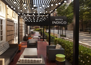 Relax in the hotel's outdoor seating area, featuring wicker furniture and a pergola with soft lighting.