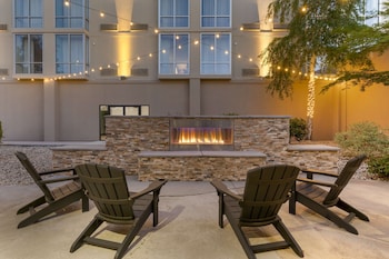 Experience the serene atmosphere of our courtyard, featuring a lush lawn, shrubs, and a cozy seating area with outdoor furniture.