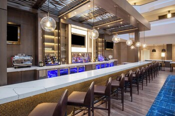 A multi-level hotel atrium with a central pool, multiple floors, and a variety of seating areas.