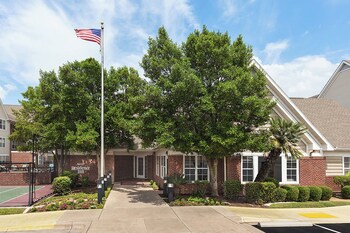 Welcome to a serene retreat surrounded by lush greenery and a beautifully landscaped entrance.
