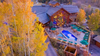 A lodge with a large central building, outdoor pool, and patio seating.