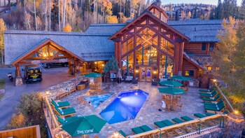 A lodge with a large central building, outdoor pool, and patio seating.