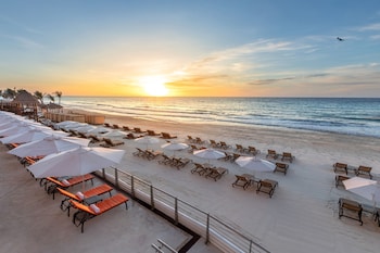 A modern hotel with a large pool area, outdoor seating, and a water slide.