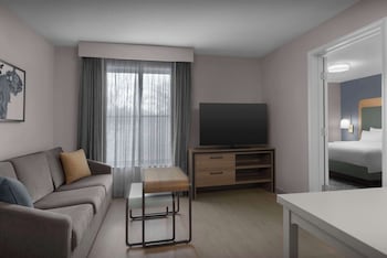 Un comedor moderno con suelo de patrón hexagonal, varias mesas y sillas, y ventanas amplias que permiten la entrada de luz natural.
