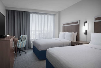 A hotel entrance with a 'Hampton Inn' sign, a glass door entrance, and a patterned floor.
