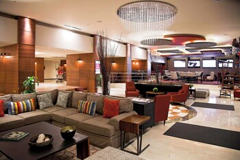 Un vestíbulo de hotel moderno con zona de estar, mostrador de recepción y pared de vidrio que ofrece vistas al vestíbulo.