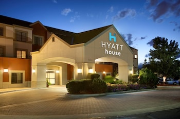 Un hôtel Hyatt House doté d’une entrée imposante, d’un jardin aménagé et offrant une vue sur un ciel dégagé.
