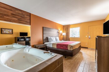 Une chambre d’hôtel avec un grand lit, une salle de bain séparée avec une baignoire, une télévision et un petit bureau.