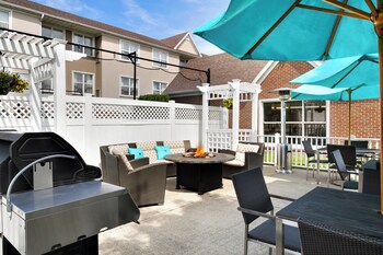 An outdoor patio with a grill, seating area, and umbrellas.