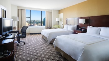 Ett Marriott-hotell med en modern fasad av glas, omgivet av andra byggnader och en historisk byggnad i bakgrunden.