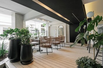 A modern indoor space with a wooden floor, black and white furniture, and large potted plants.