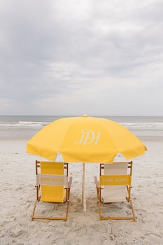 Une vue sur la plage, avec une longue étendue de sable, une jetée et une zone résidentielle comprenant des maisons et une piscine.