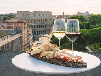 A couple sitting by a pool with a view of the Colosseum in Rome.