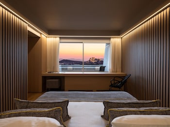 Habitación con vista a un paisaje urbano nocturno, que incluye una lámpara, esferas decorativas y libros sobre una mesa de vidrio.