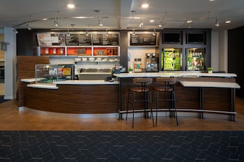Enter the contemporary Courtyard by Marriott through a covered walkway, leading to a spacious interior with multiple balconies and large windows.