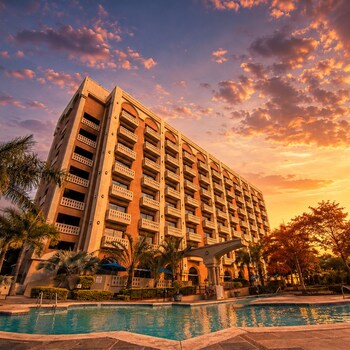 Un hotel con varios balcones, piscina y palmeras.