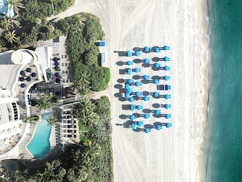 Un paisaje urbano costero con rascacielos, una playa y aguas azules cristalinas.