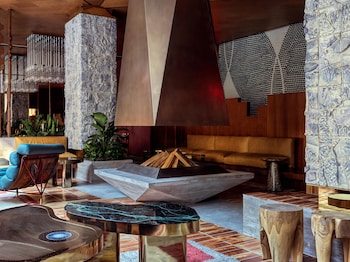 A hotel room with a bed, a bedside table, and a wall unit.