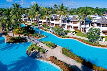 Enjoy a serene beachfront setting with calm waters and lush palm trees.