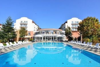 Una piscina con sillas de descanso y un edificio con balcones al fondo.