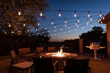 An outdoor patio with a fire pit, string lights, and outdoor furniture.